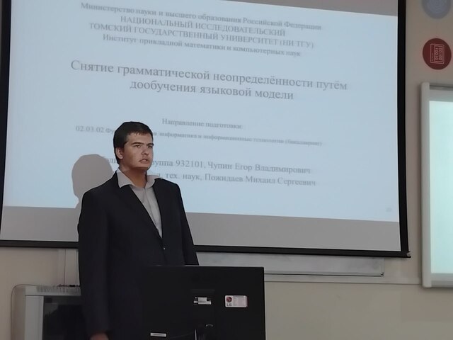Молодой человек в костюме делает доклад перед аудиторией