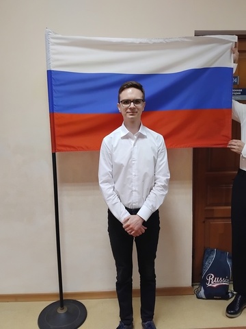 Молодой человек стоит на фоне российского флага