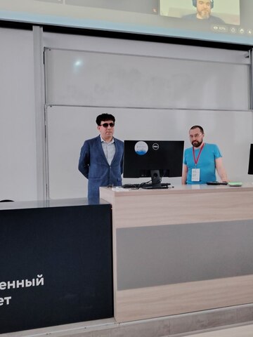 Мужчина стоит на&nbsp;месте преподавателя в&nbsp;аудитории и произносит речь.